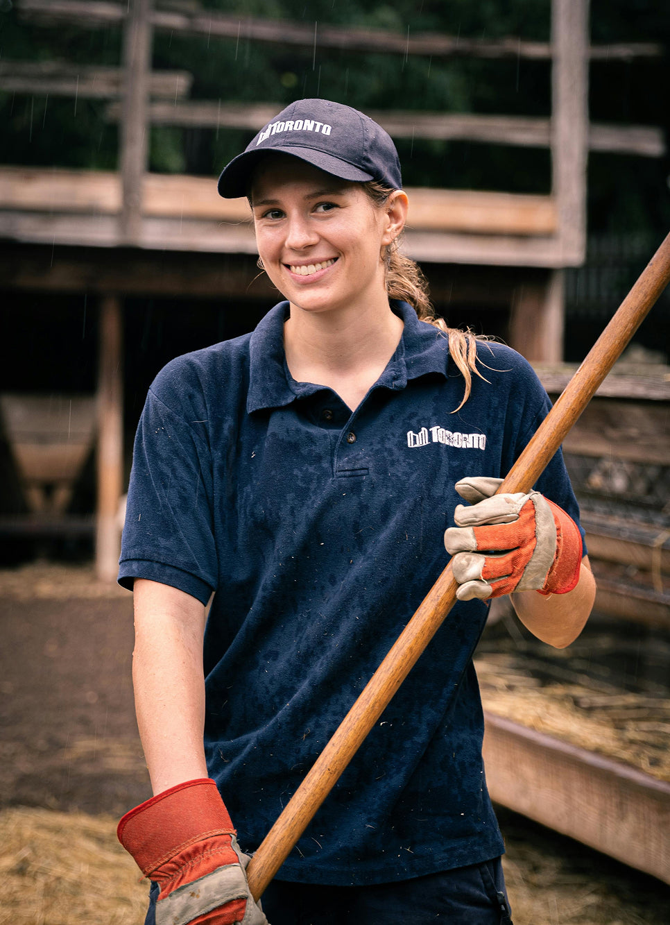 Person wearing a blue shirt and cap, holding a long tool, with a blurred background.