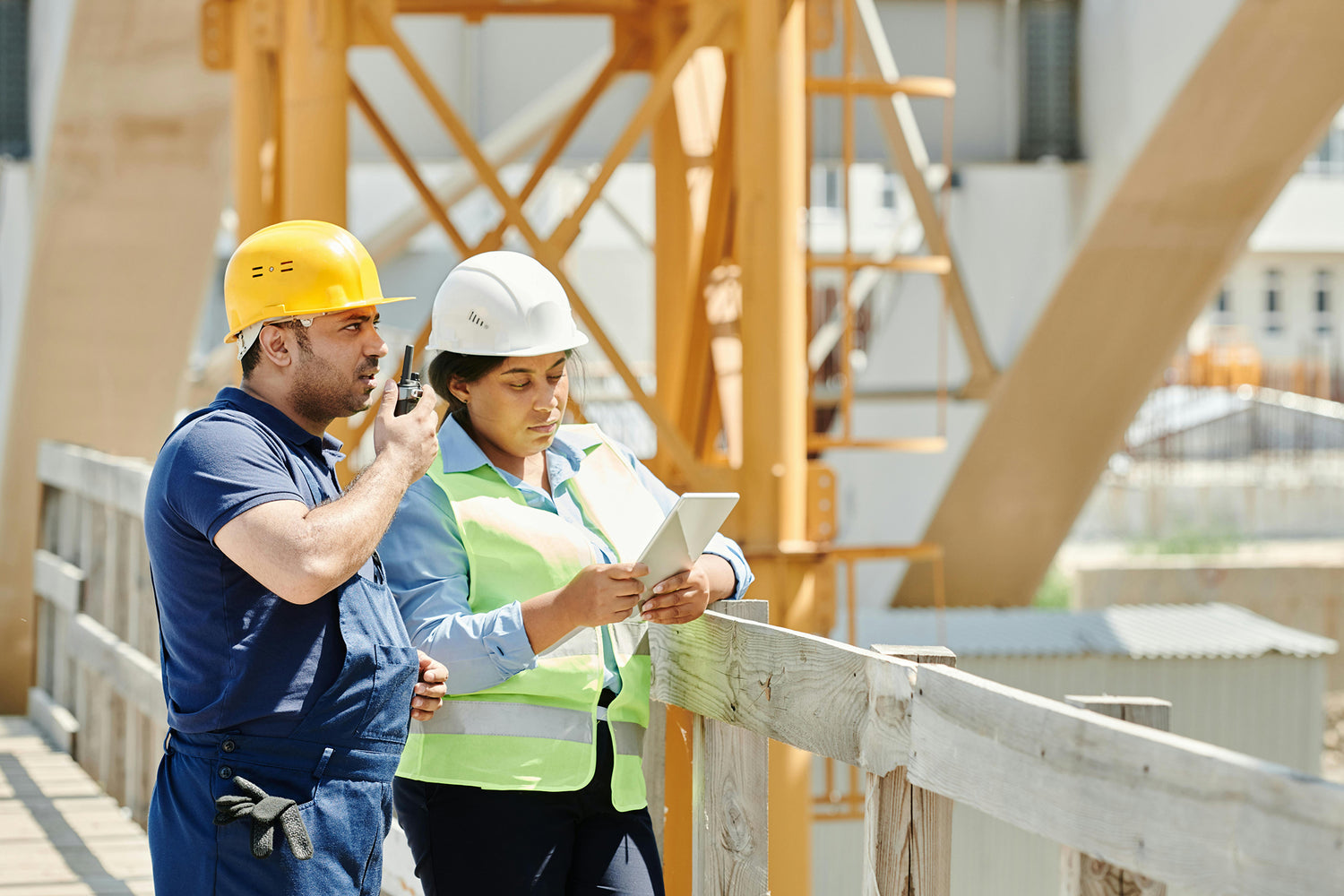 Two construction workers on a site with a crane in the background